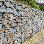 Крупный план текстуры габионной стены с плотной укладкой камня за оцинкованной сеткой