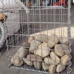 Наполнение сварного габионного короба гладким речным камнем на строительной площадке
